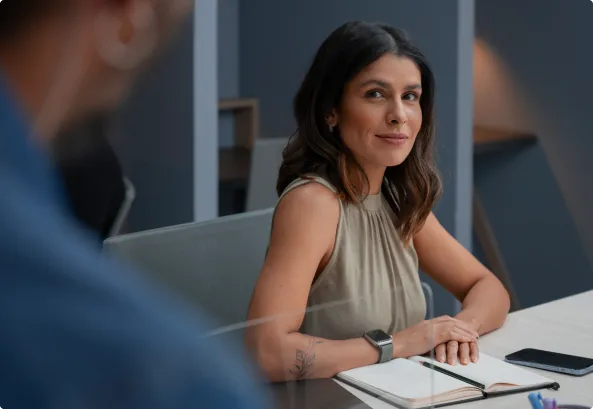 A woman in an office looking directly at us, calm and smiling